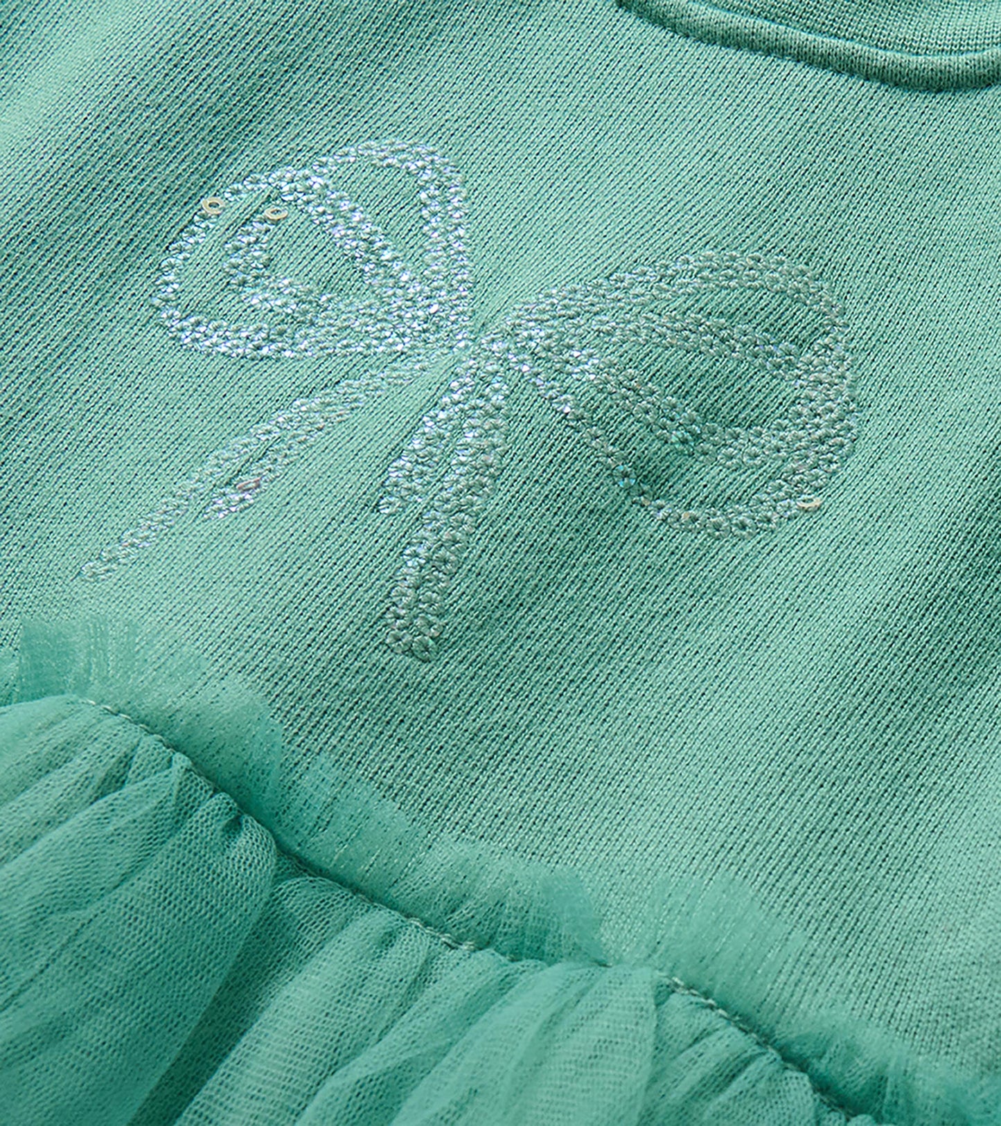 Close-up of the chest showing a sequin bow detail on the oil blue dress