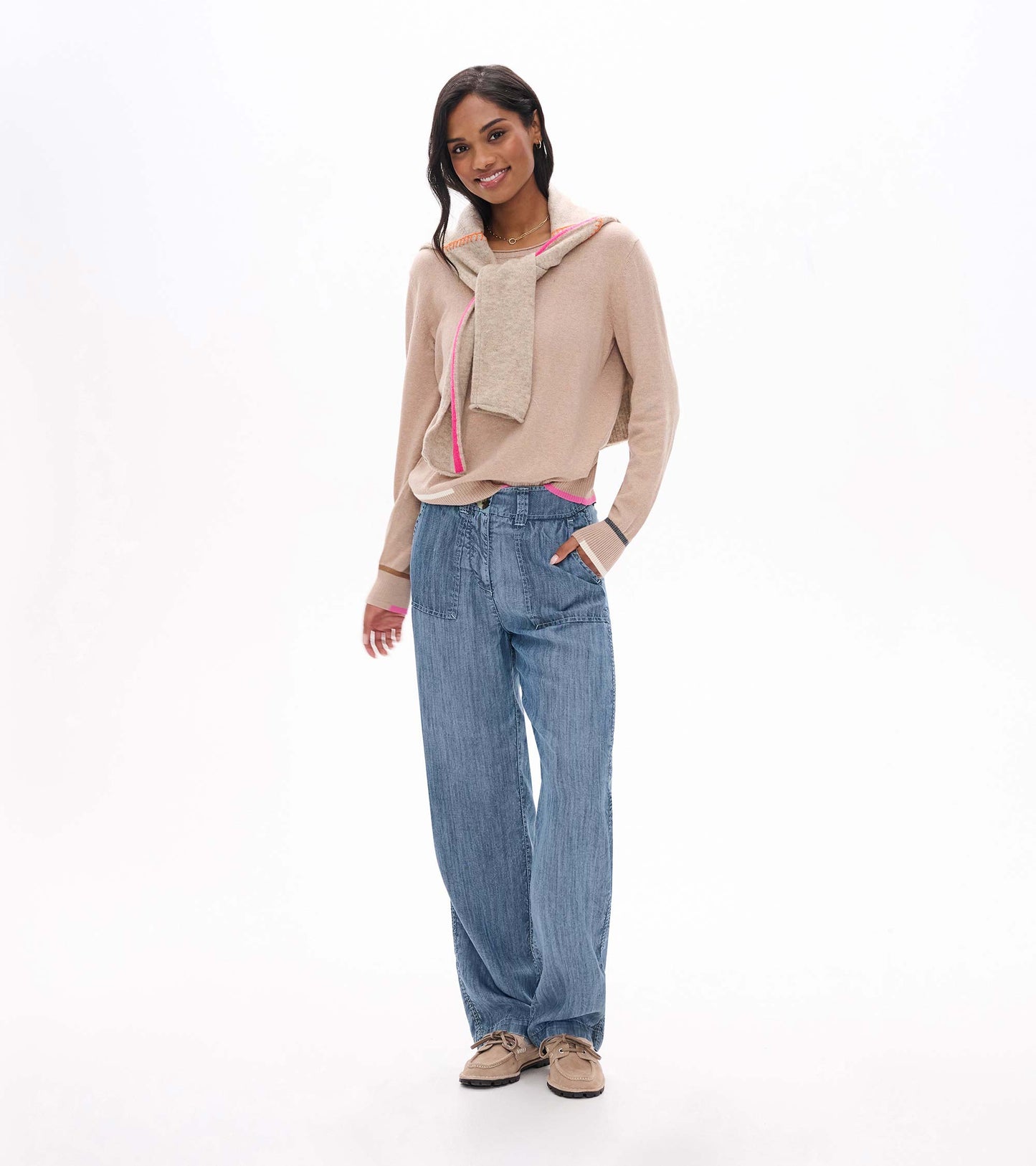 Model wearing oatmeal melange crew neck sweater with bright pink trim, shown tied over shoulders