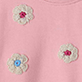 Pink fabric with small embroidered flowers in white, blue, and red