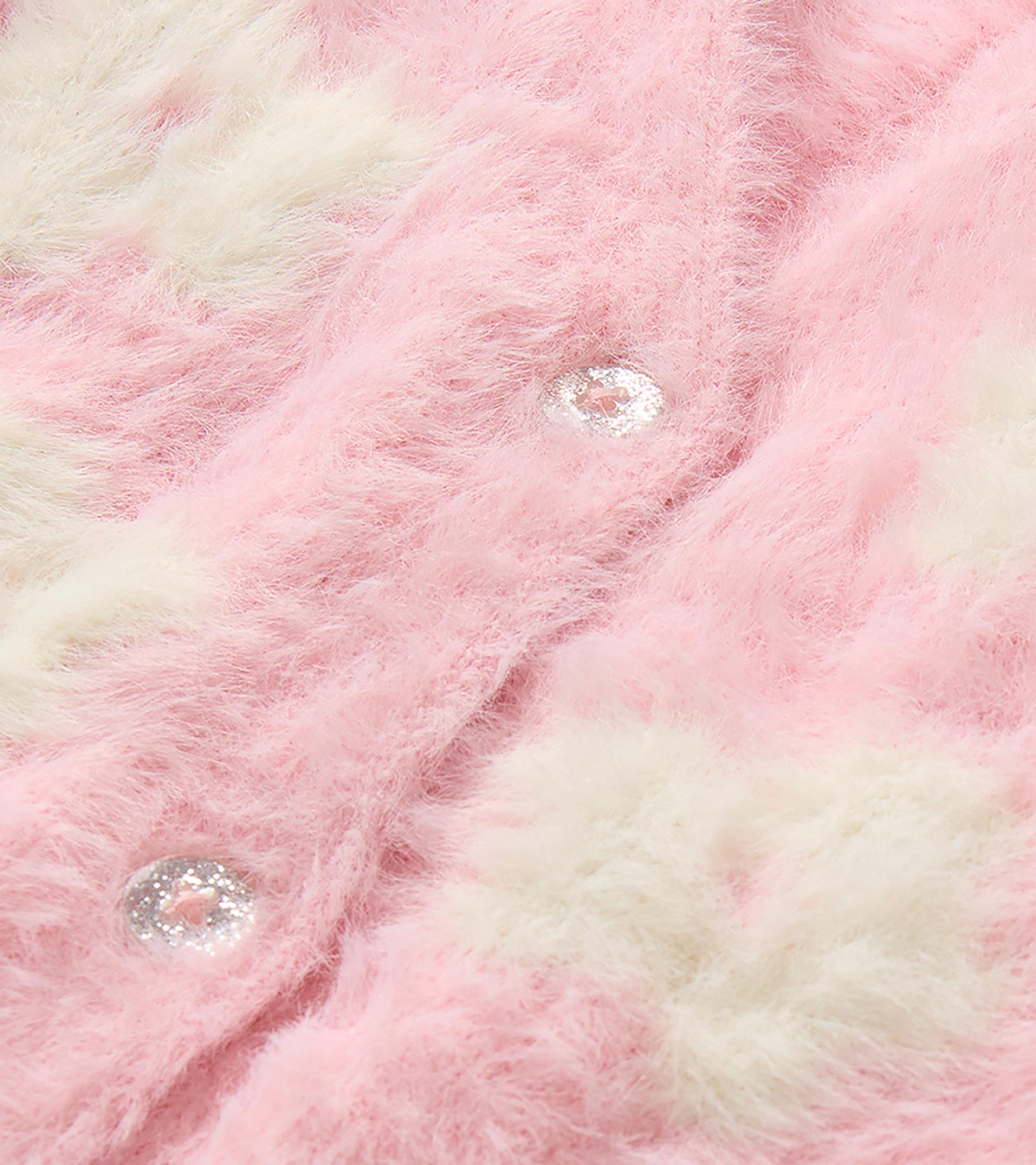 Close-up of pink fuzzy cardigan with cream flower pattern and glitter front buttons