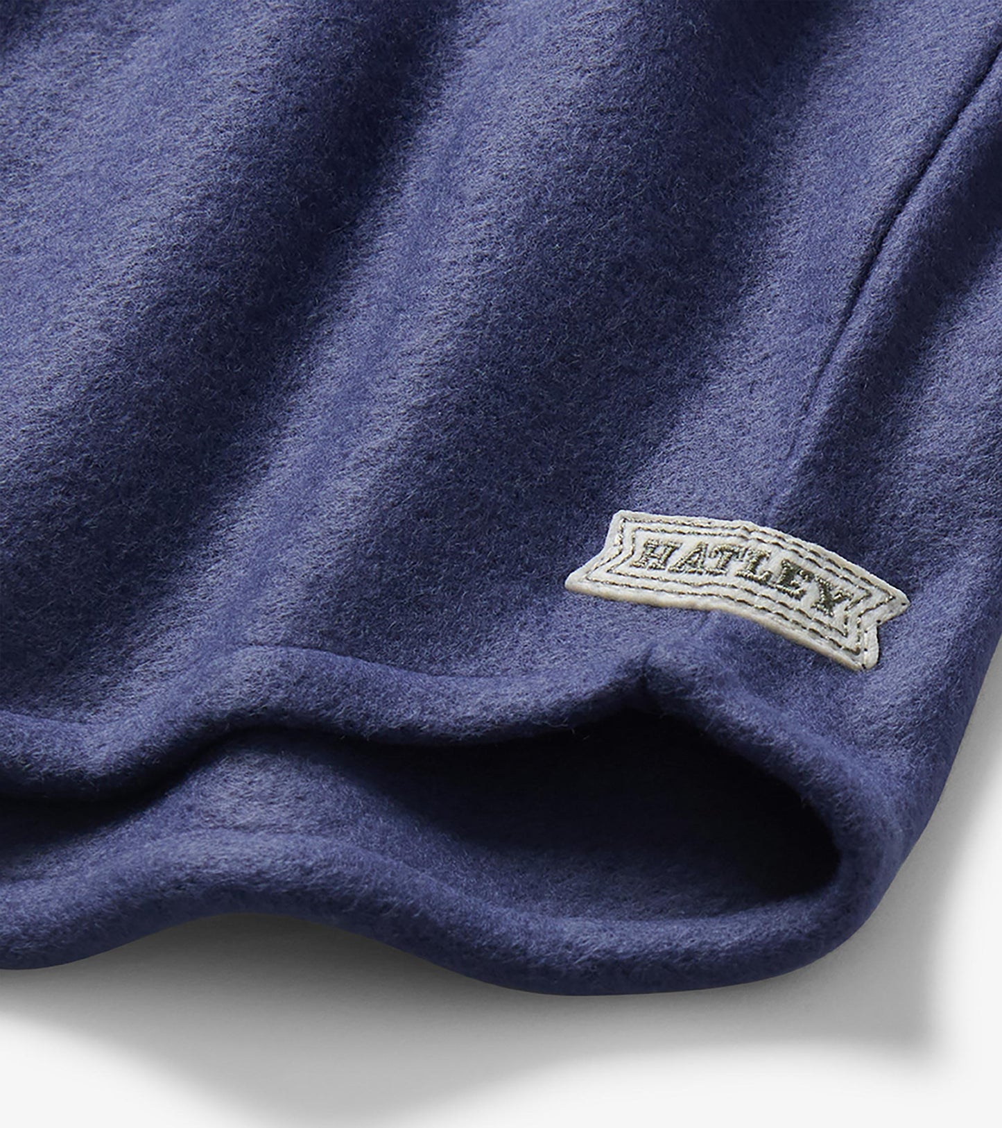 Close-up of patriot blue fleece shirt hem with visible Hatley logo patch