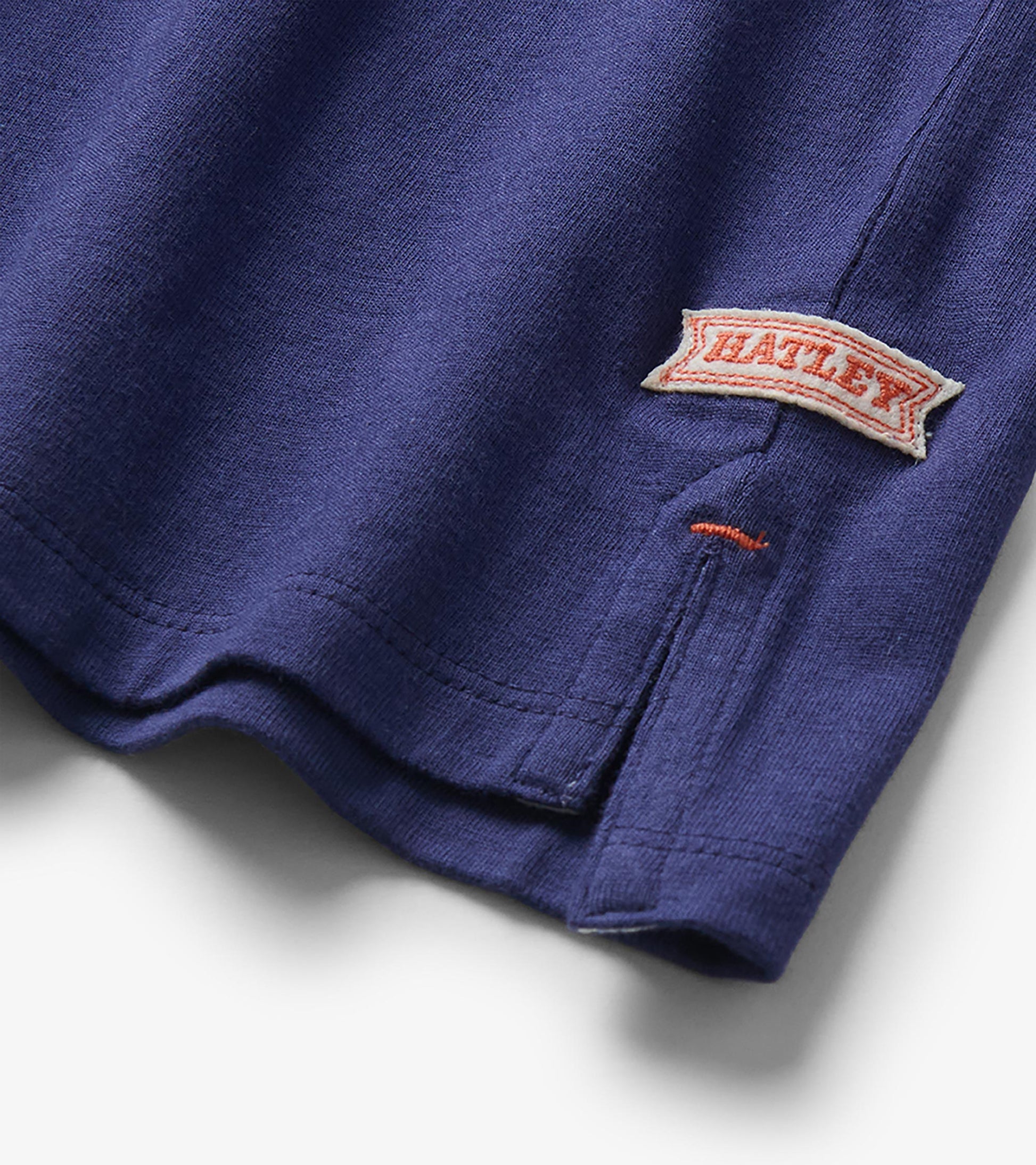 Close-up of side hem slit on patriot blue rugby shirt with visible Hatley logo tab