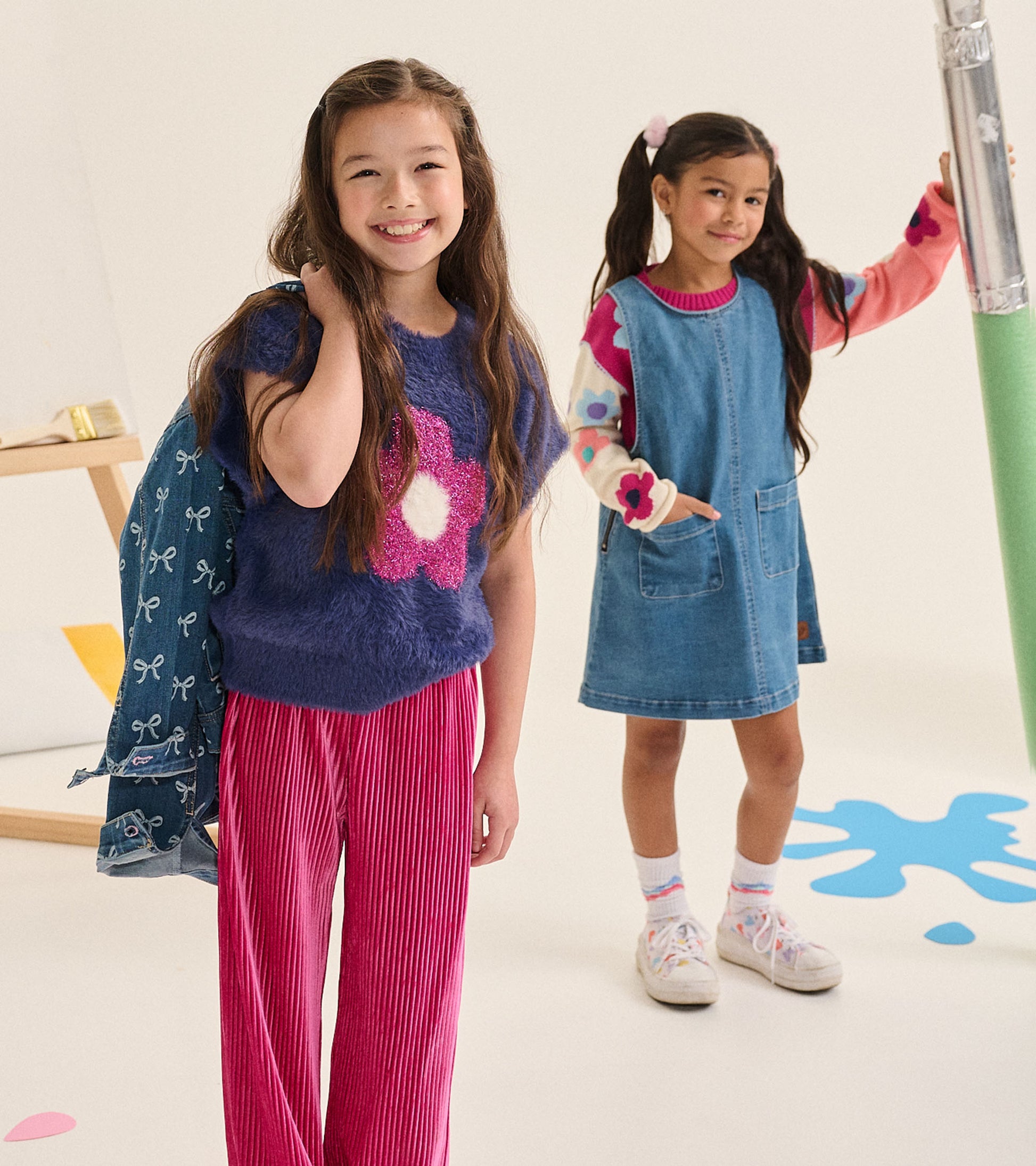 Girl wearing fuzzy blue sweater vest with bright pink flower, styled with pink pants