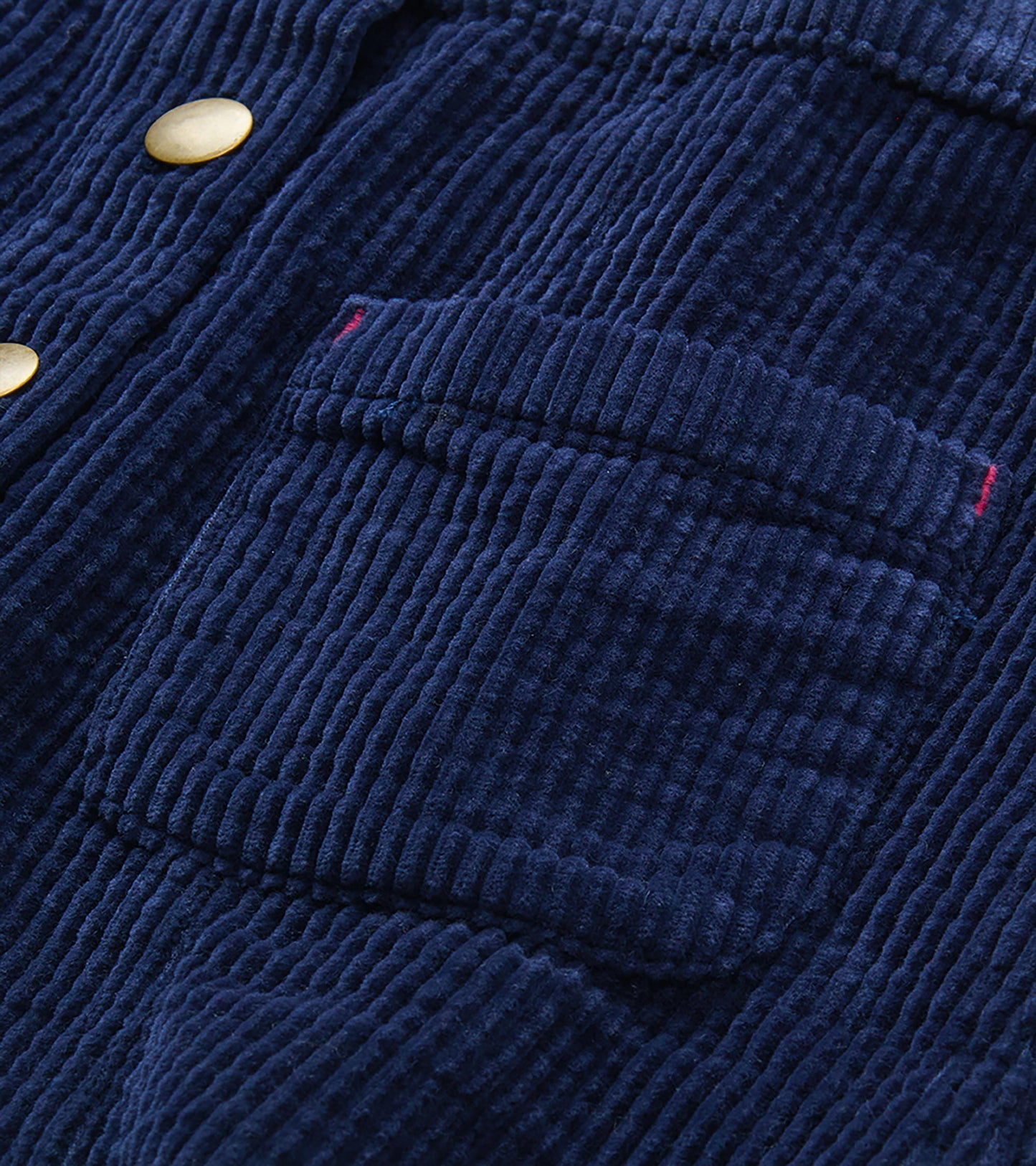 Close-up of patriot blue corded skirt with gold snaps, patch pocket, and pink stitch accents