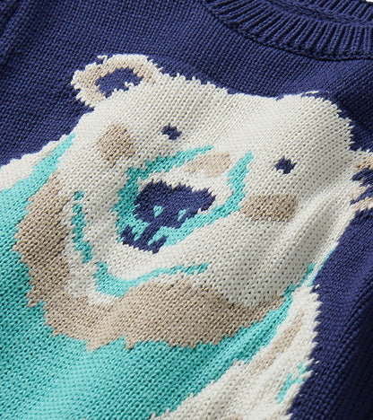 Close-up of polar bear knit graphic on navy sweater with bright teal scarf detail