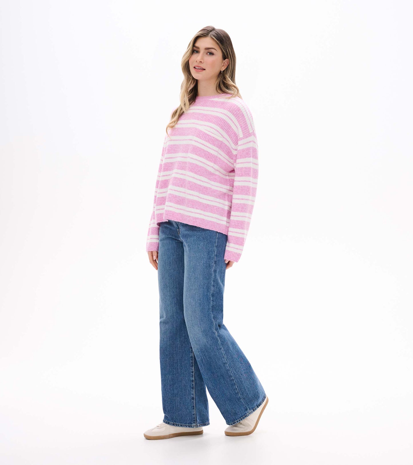 Side view of pink and cream striped sweater on model with dropped shoulders and long sleeves