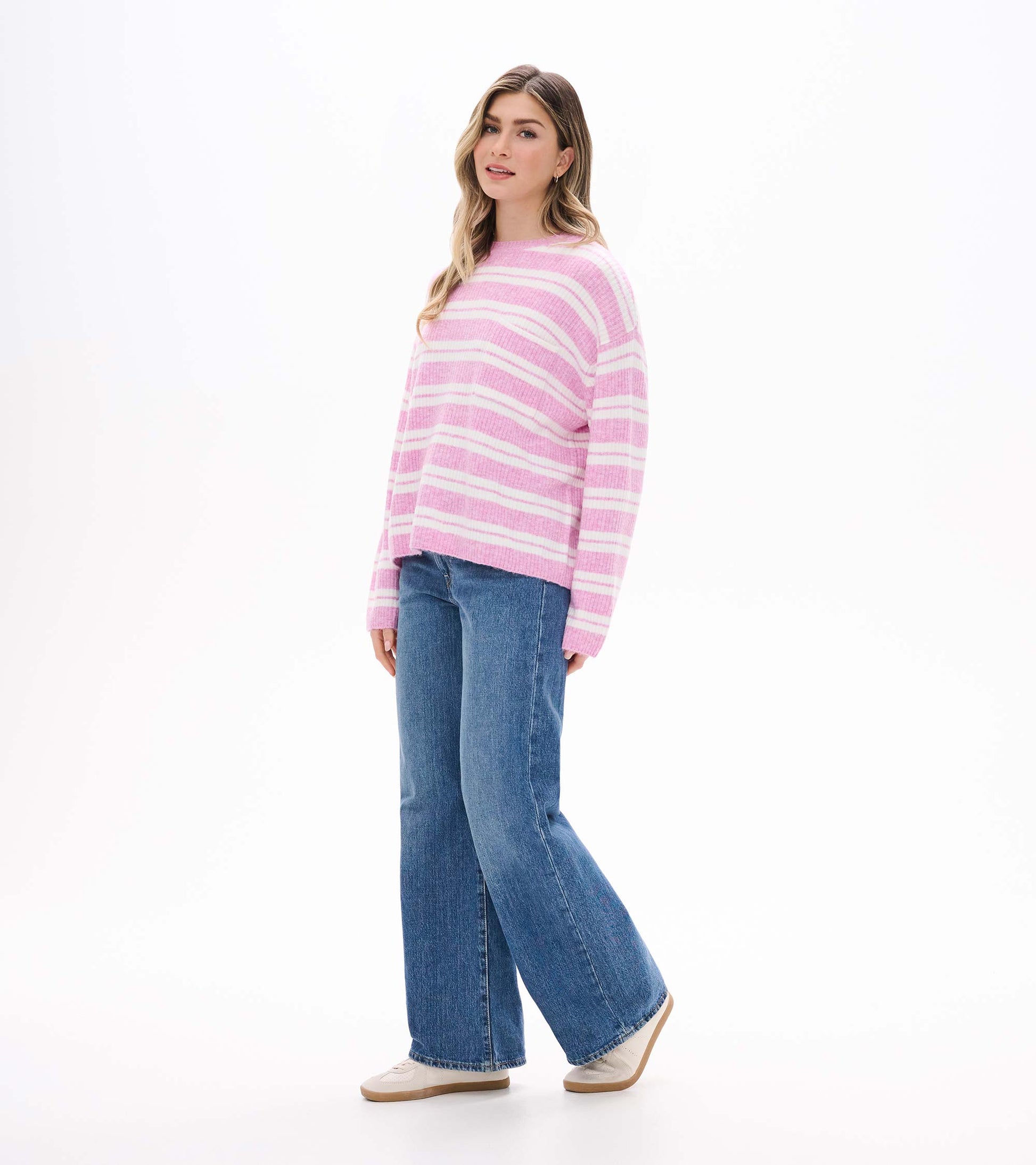 Side view of pink and cream striped sweater on model with dropped shoulders and long sleeves