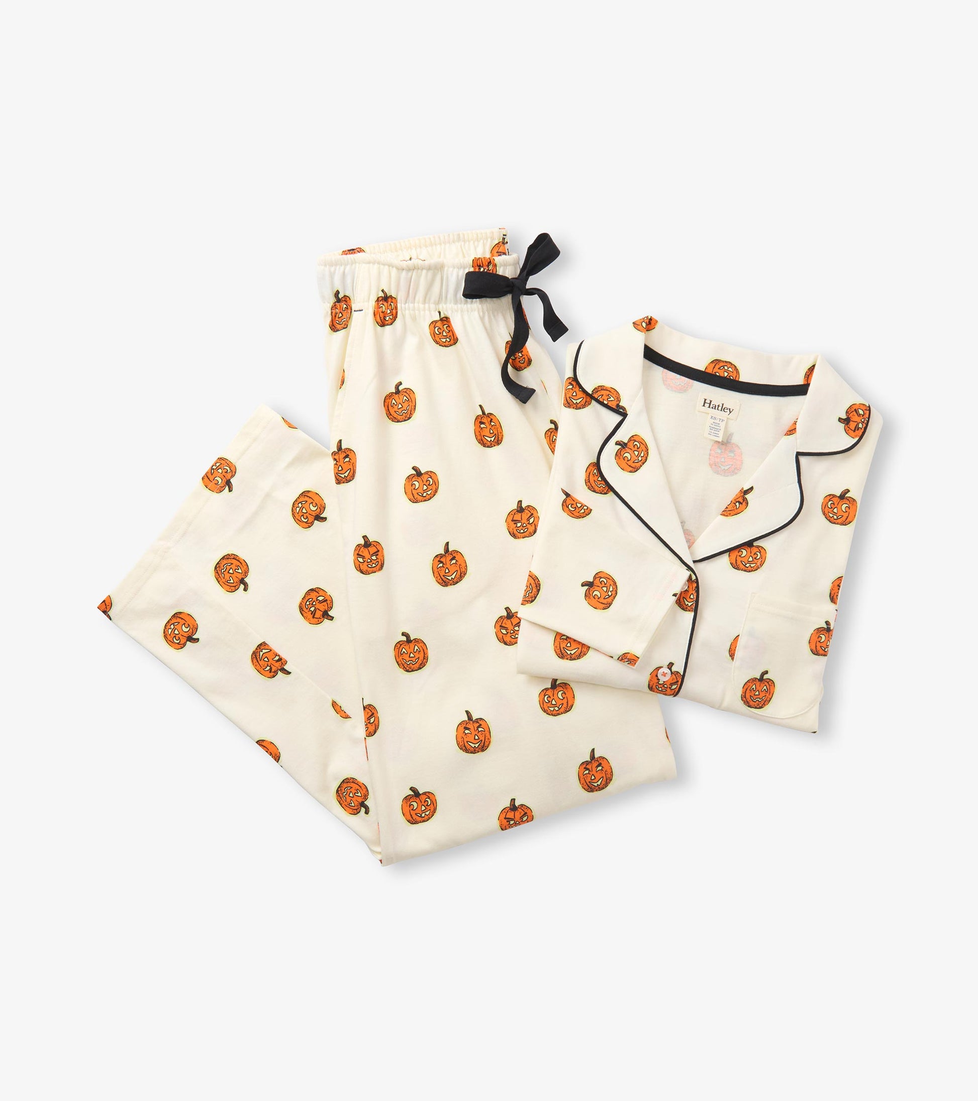 Folded cream pajama set with orange pumpkin print, black piping, and black ribbon waist tie