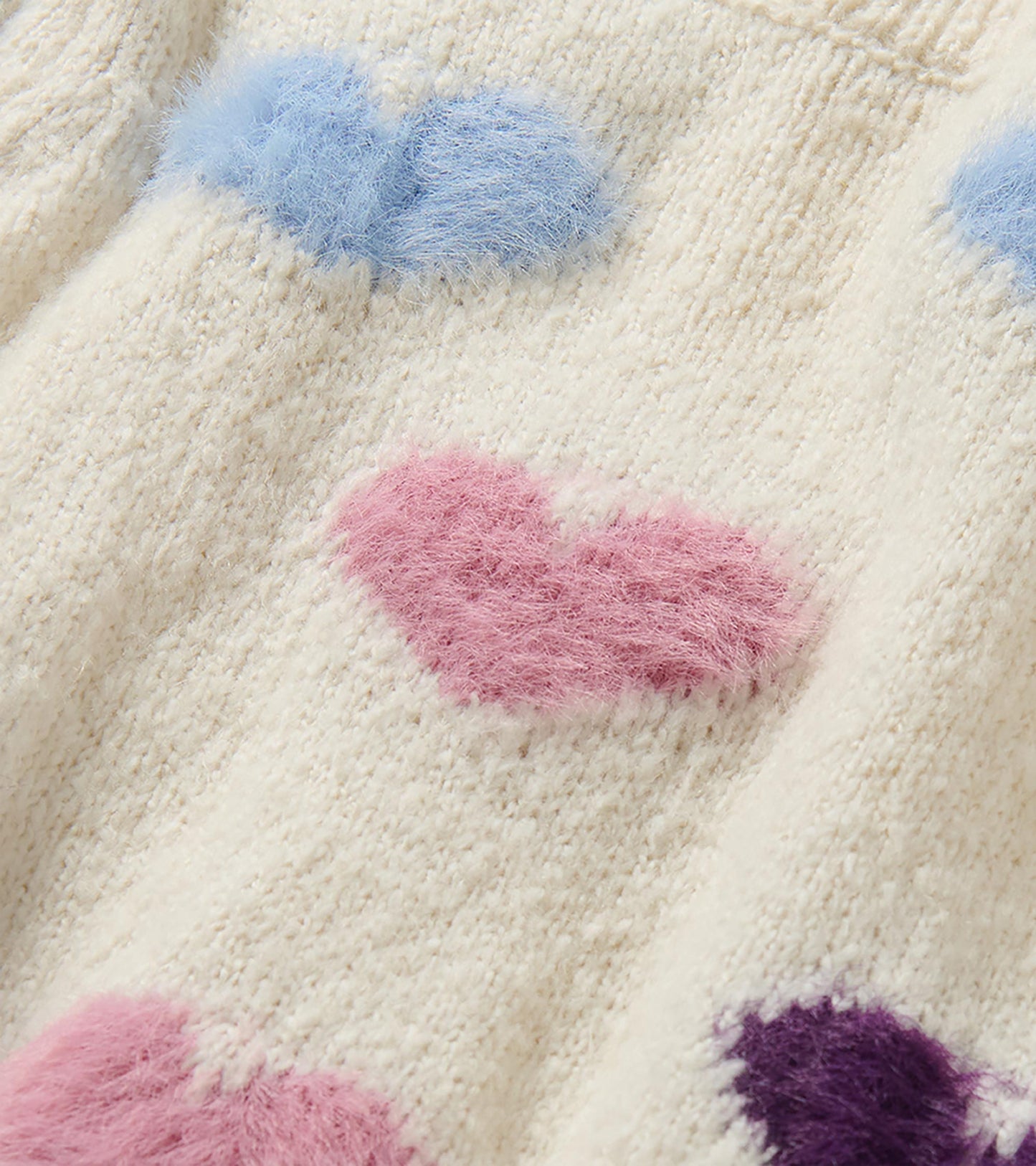 Close-up of cream knit sweater with fuzzy blue, pink, and purple heart pattern