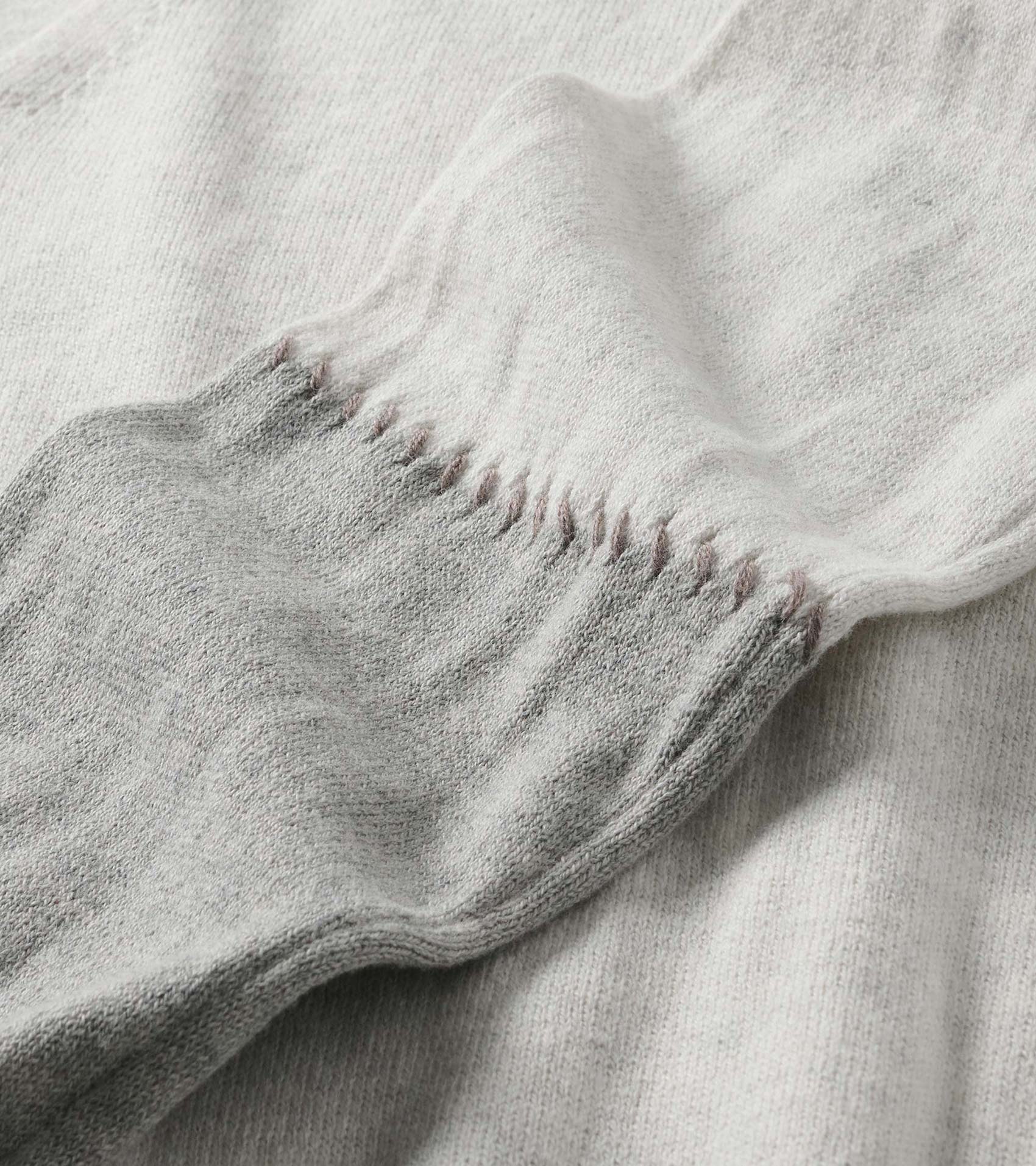 Close-up of pale grey melange sweater dress sleeve with stitched detail at the cuff