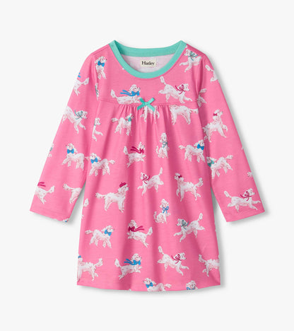 Front view of girls pink nightdress with white poodle print, teal neckline, long sleeves, and teal bow at chest