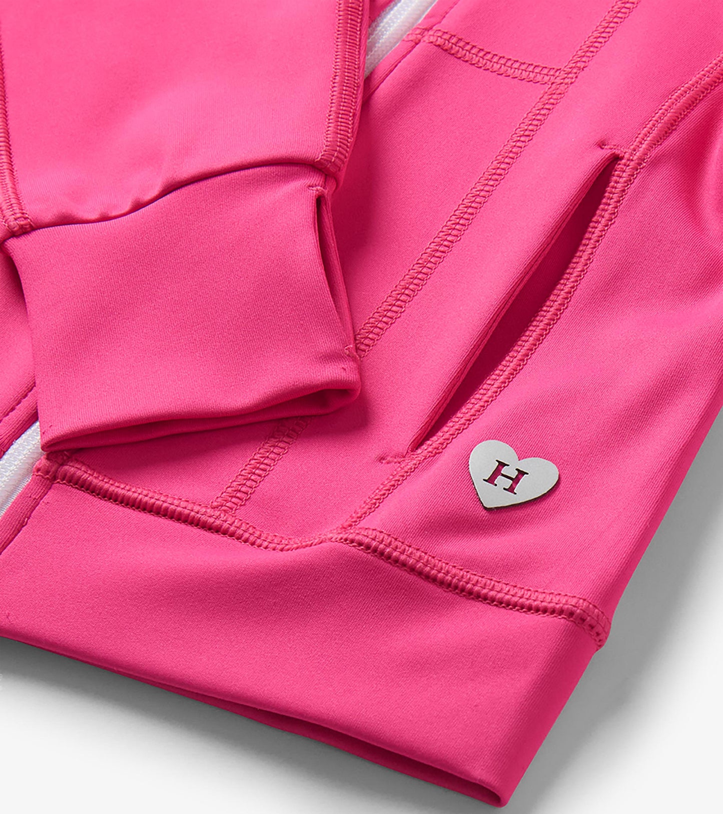Close-up of bright pink jacket cuff and front pocket with seam detailing and heart-shaped H charm