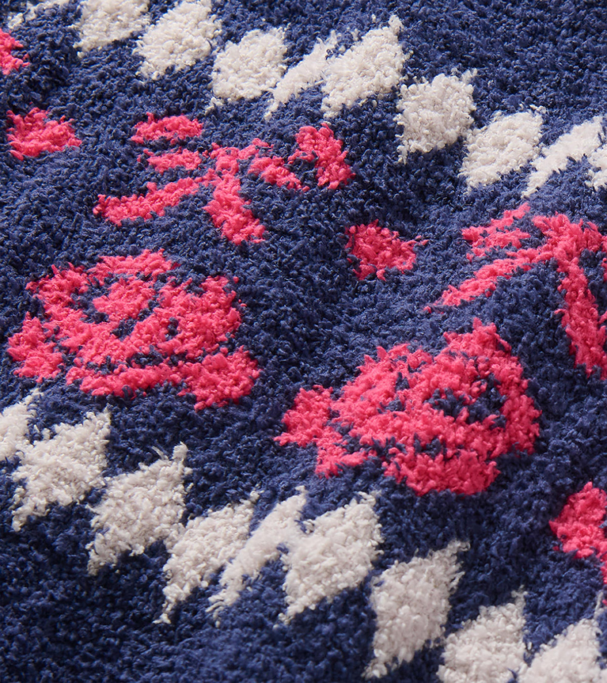 Close-up of navy fuzzy knit with pink bow and rose pattern and white diamond details