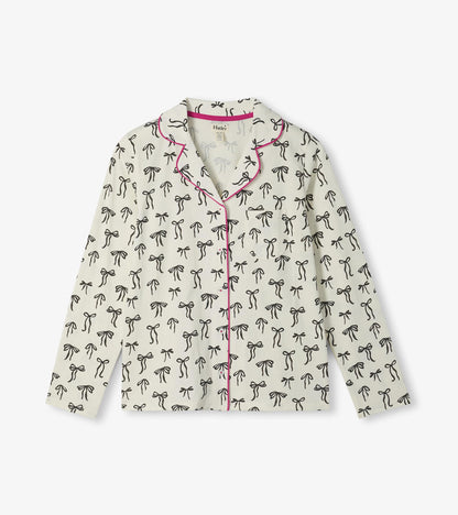 Cream pajama top with black ribbon bow print, pink piping, and chest pocket