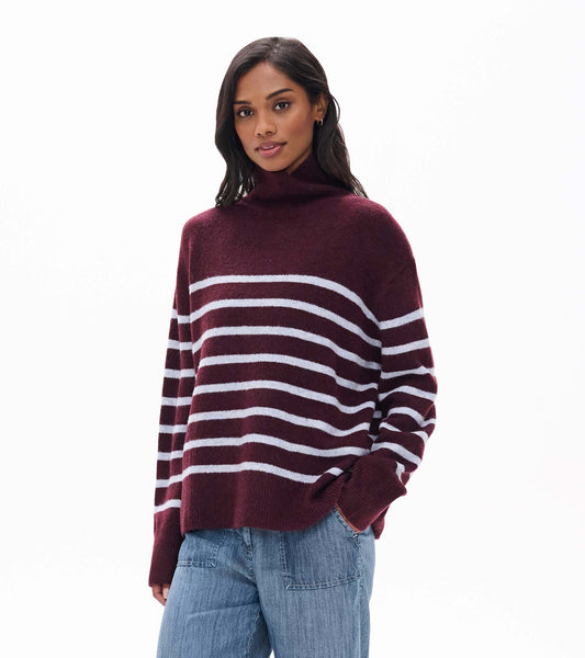 Close view of rumba red mock neck sweater with white horizontal stripes, shown on model