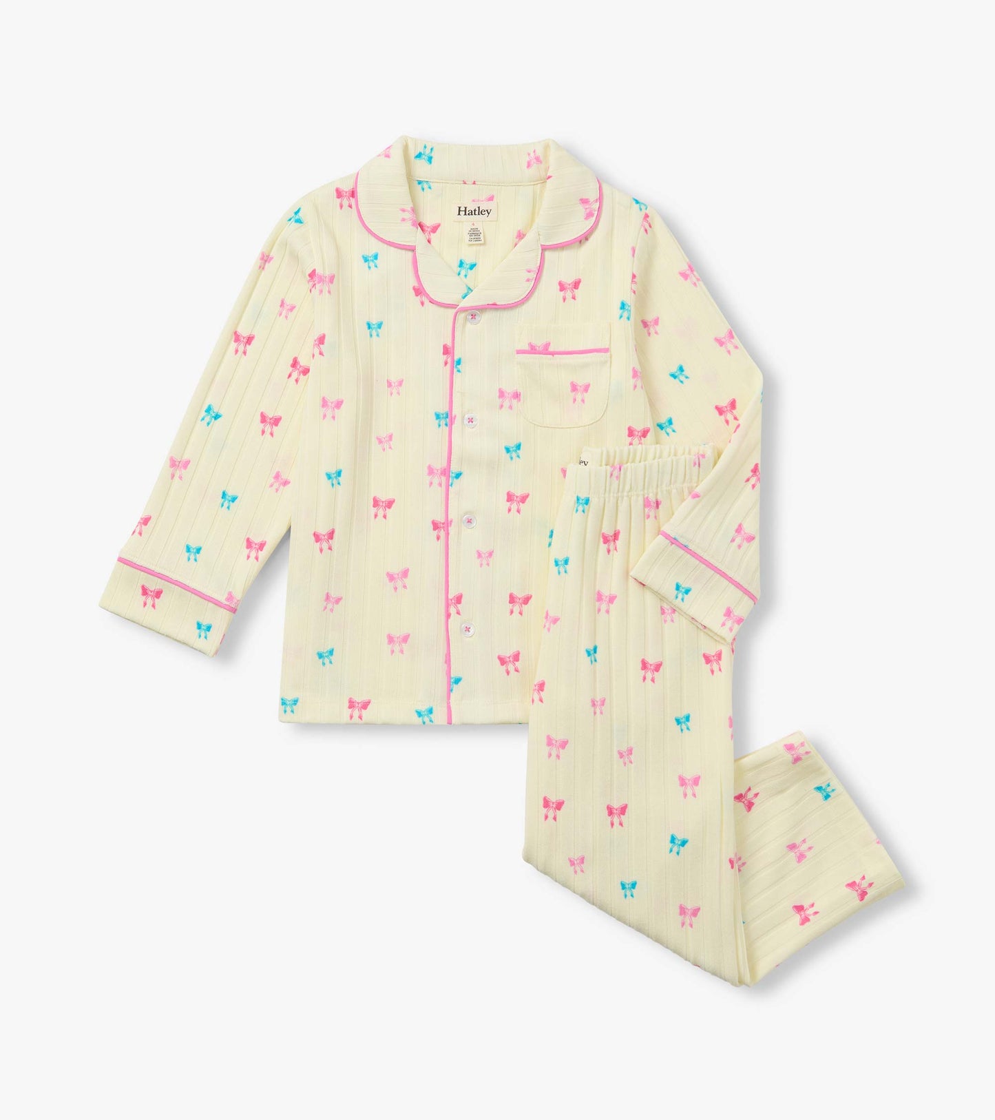 Kids pajama set with pale yellow button-up top and pants, pink piping, and pink and blue bow print