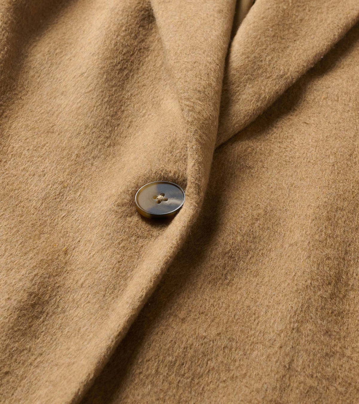 Close-up of the camel brown jacket fabric and single button detail
