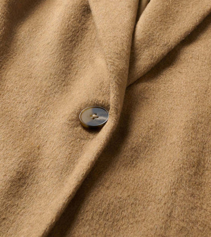 Close-up of the camel brown jacket fabric and single button detail