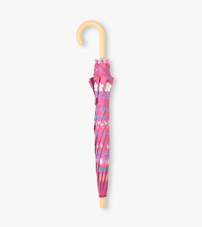 Closed pink umbrella with tiny flower print and curved light wood-tone handle