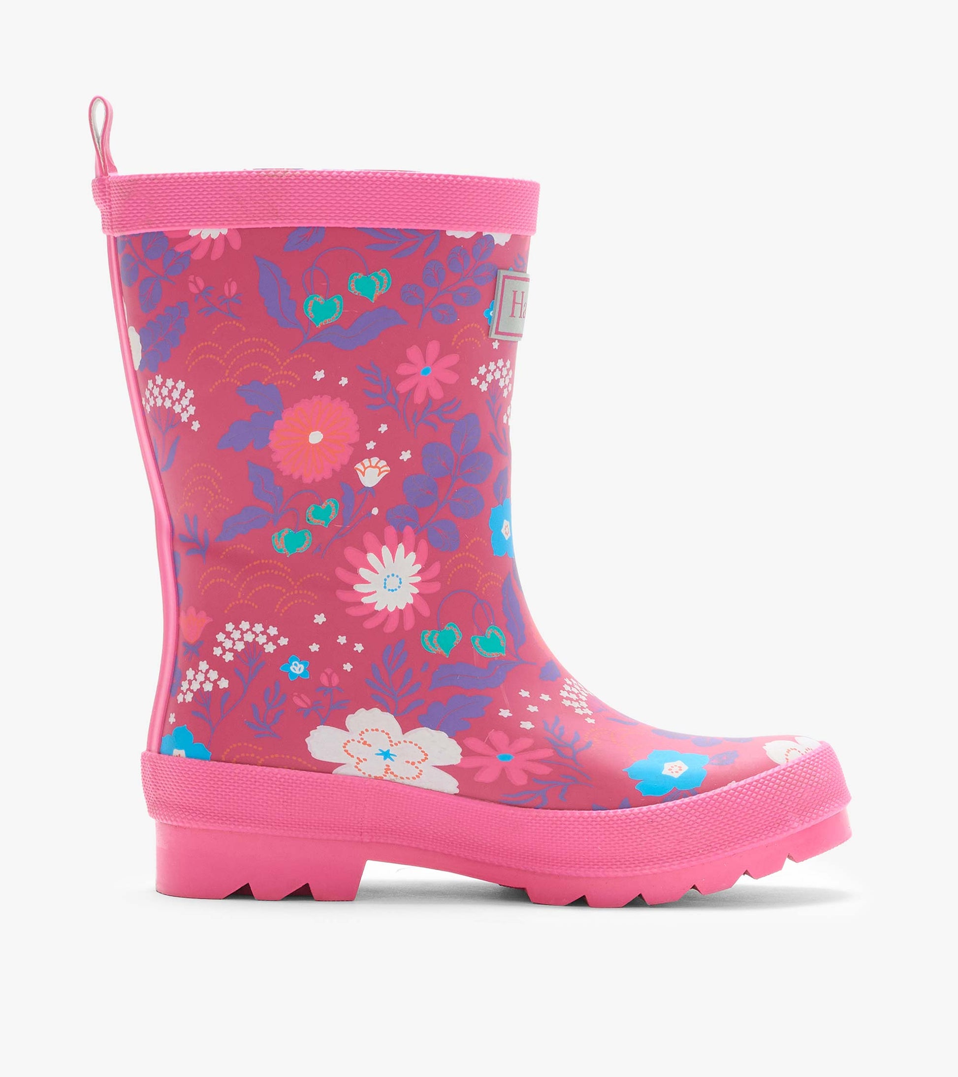 Side view of a pink rain boot with colorful tiny flower print, pull tab, and treaded sole