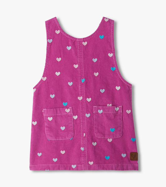 Front view of pink pinafore dress with embroidered hearts, patch pockets, and a sleeveless scoop neck