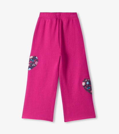 Back view of berry pink wide leg track pants with floral heart patches on the backs of both legs