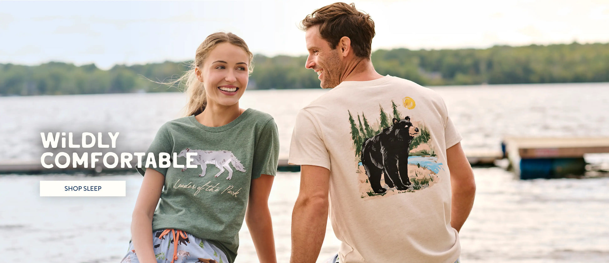 Promotes sleepwear collection. Showing two models in graphic sleep tees by a lakeside dock.