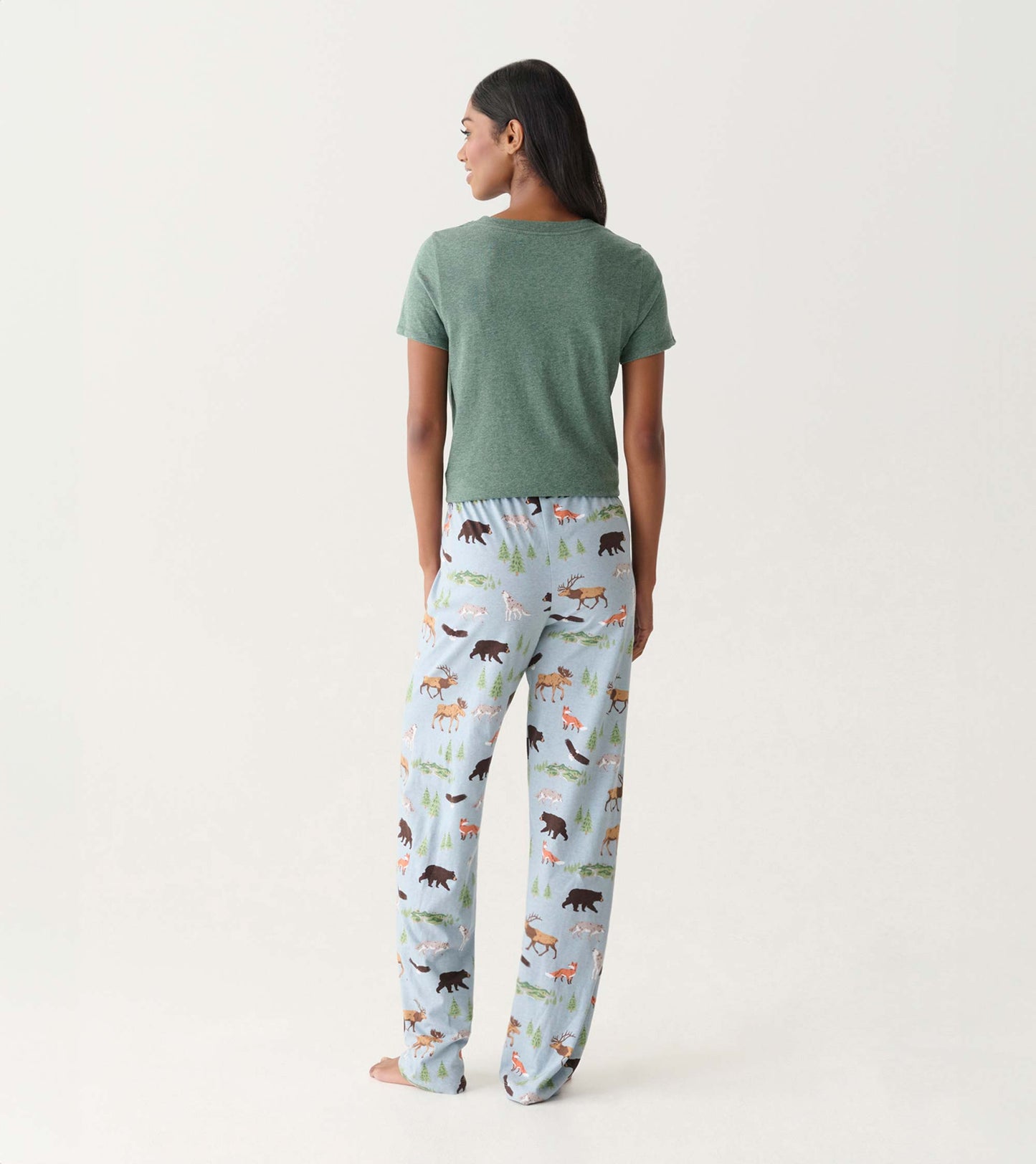 Back view of light blue cotton pajama pants with woodland animal and tree print, worn with a green T-shirt