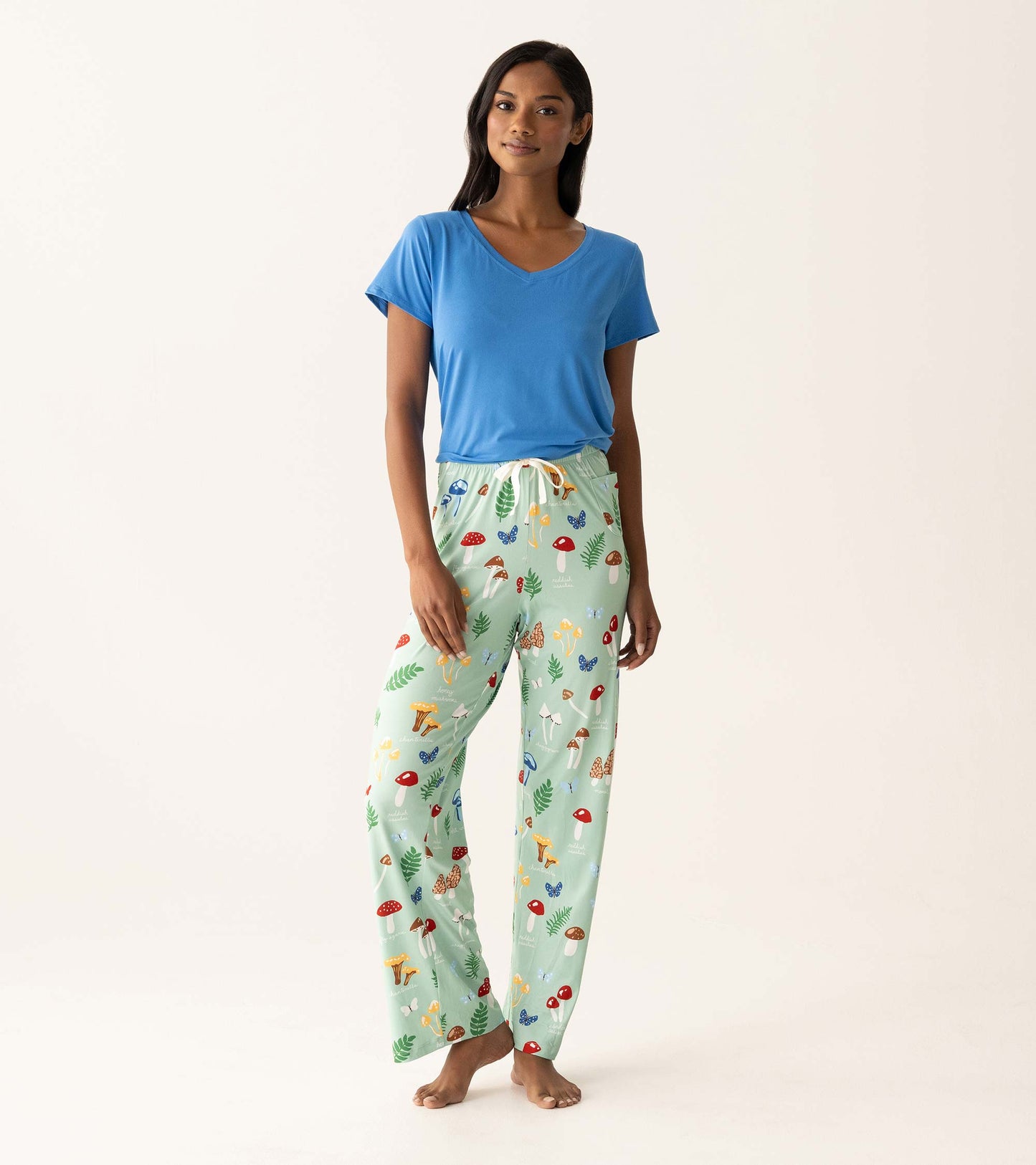 Model wearing mint green mushroom-print pajama pants with a blue V-neck T-shirt, front view.
