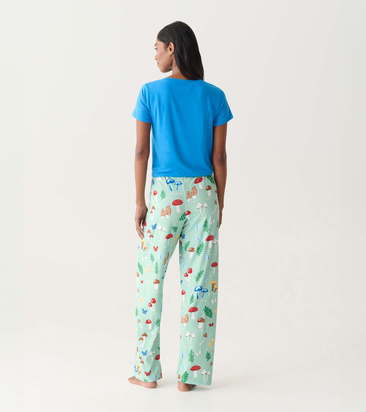 Back view of mint green pajama pants with colorful mushroom print, worn with a bright blue T-shirt
