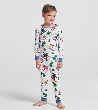 Child wearing white ski print pajama set with blue trim, trees, snowflakes, and skiing animals