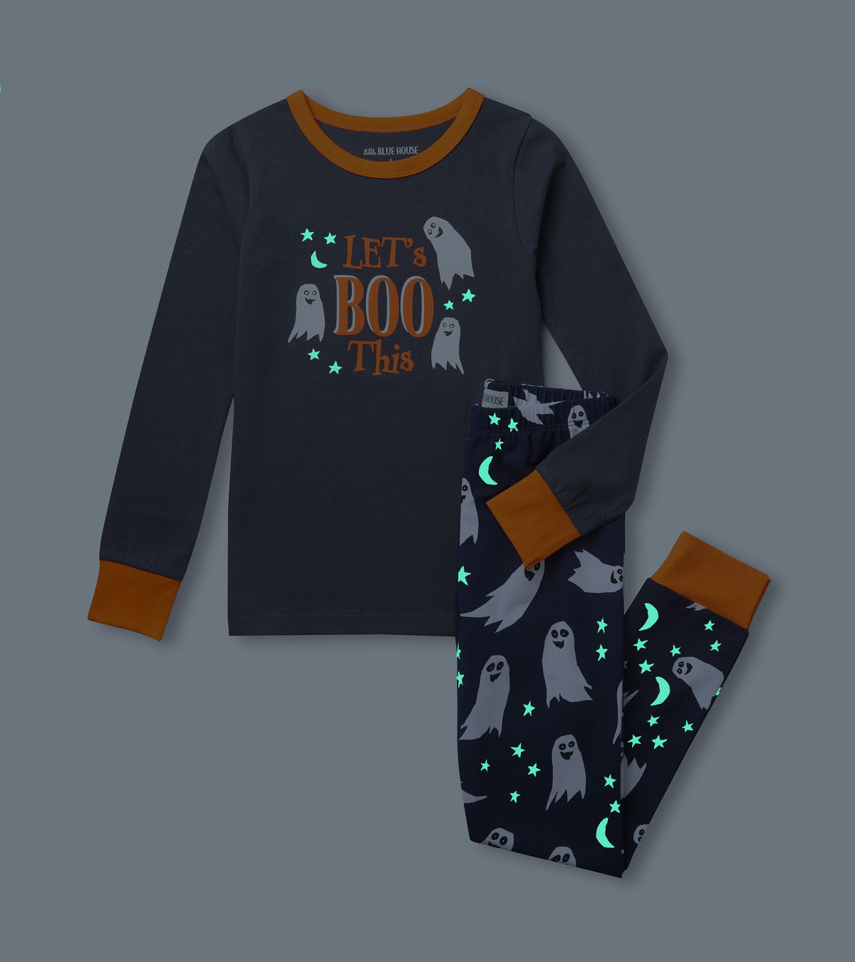 Kids ghost pajama set shown in the dark with glowing stars and moons on the top and pants