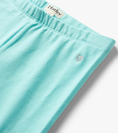 Light aqua girls bike shorts with elastic waistband and small embroidered heart logo, close-up view