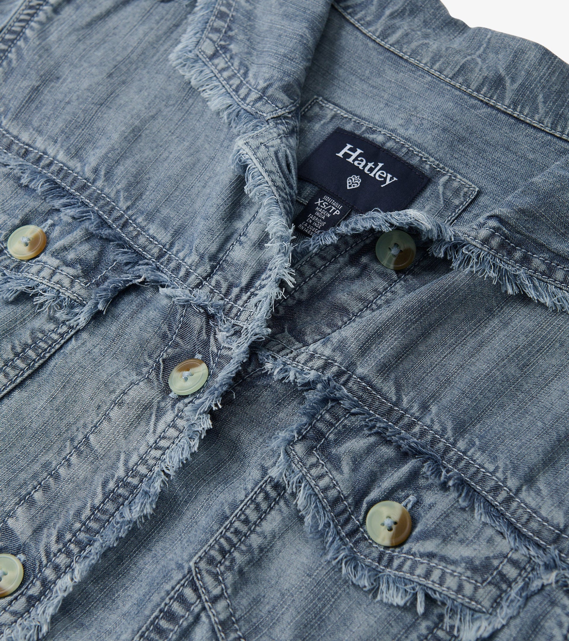 Blue acid wash linen jacket with frayed edges and button closures, featuring two front pockets.