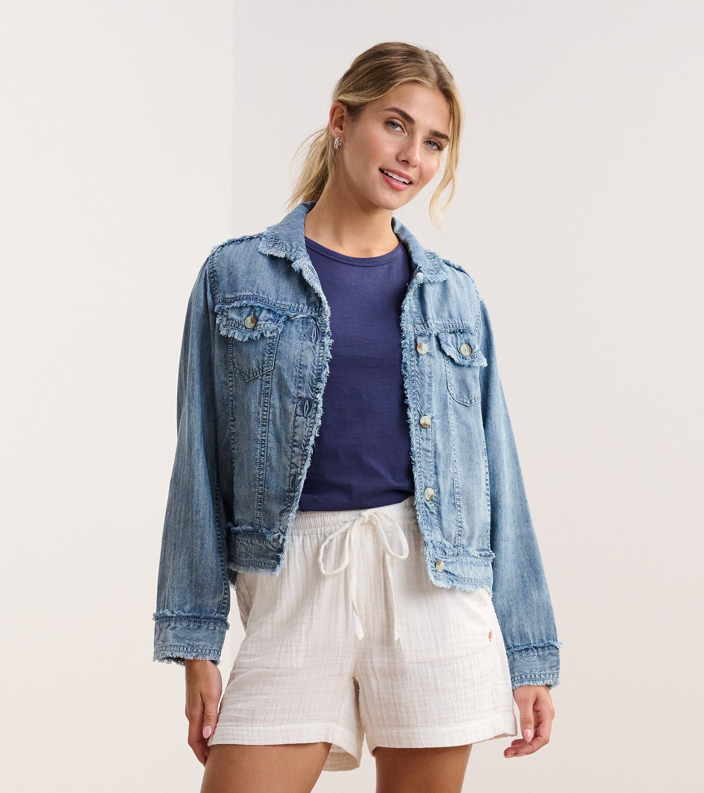 Blue acid wash linen jacket with frayed edges, styled over a navy top and white shorts.