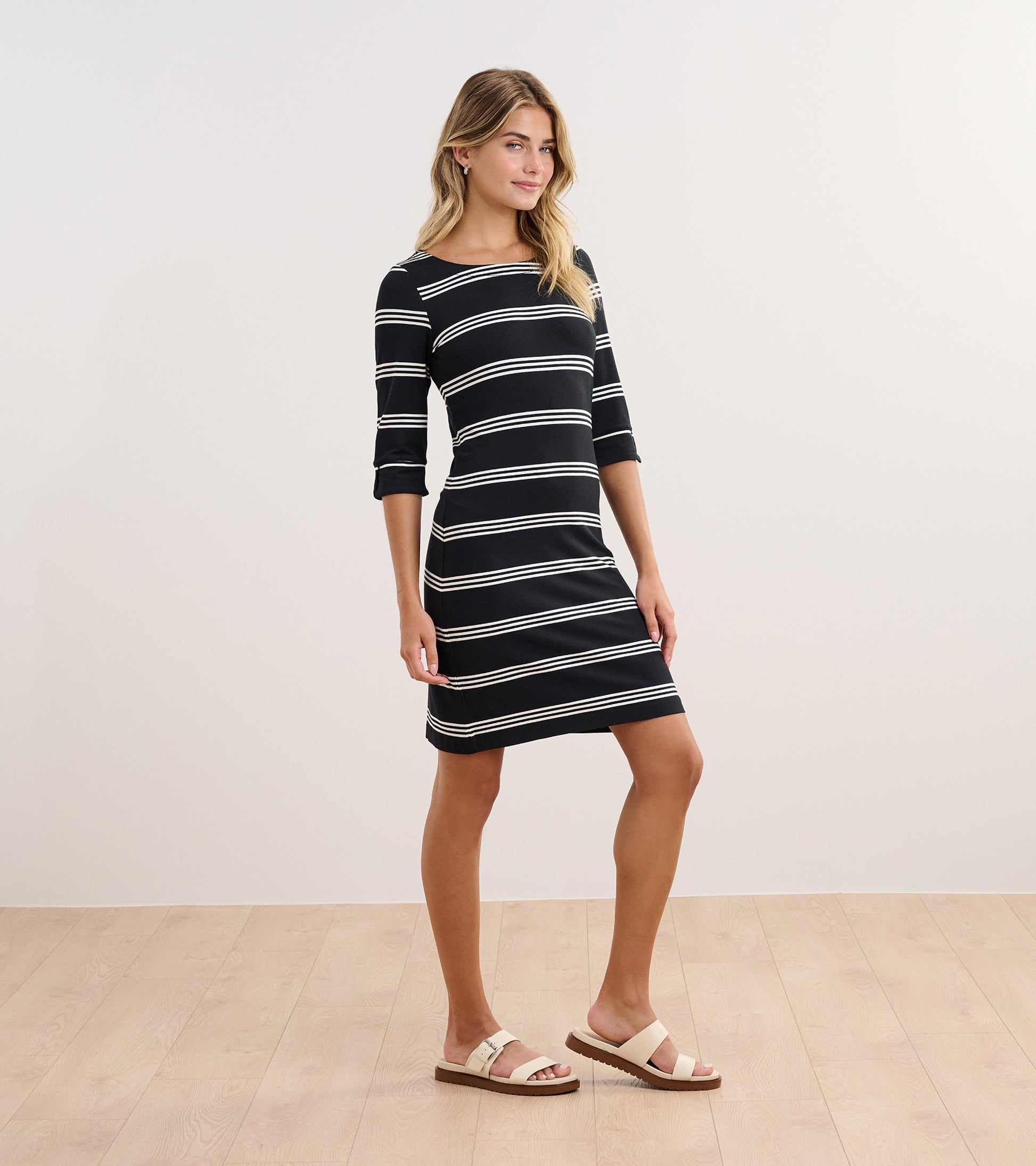 Black and white striped dress with three-quarter sleeves, fitted silhouette, and round neckline.