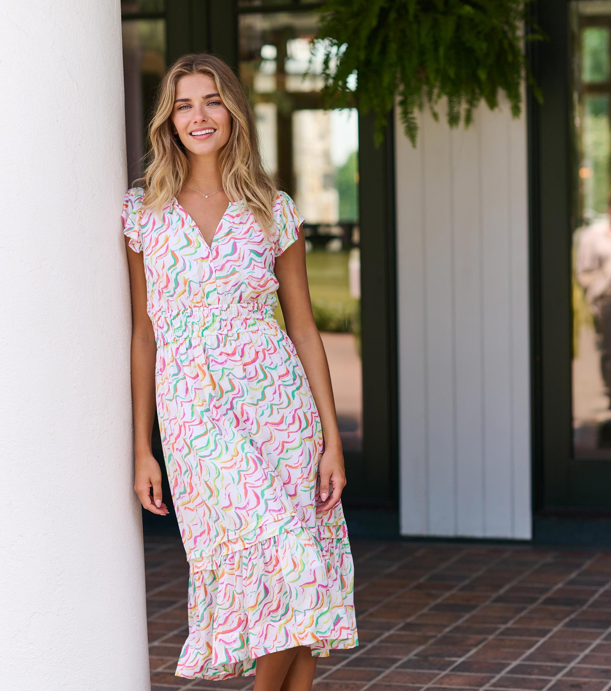 Midi dress featuring wavy stripes in pastel colors, with a fitted waist and ruffled hem, styled with short sleeves.