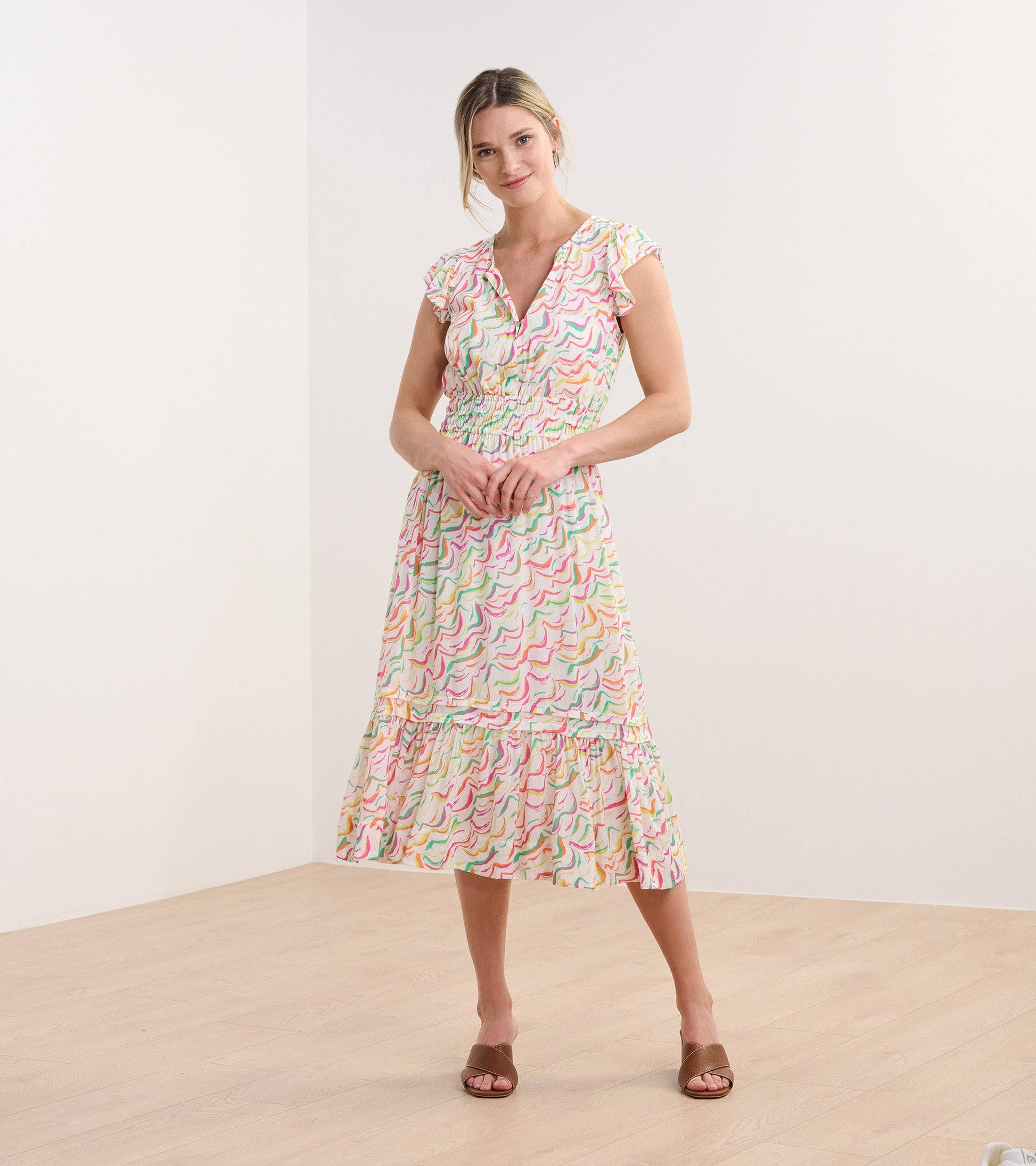 Midi dress featuring wavy stripes in pastel colors, with a smocked waist and ruffled sleeves, ideal for casual wear.