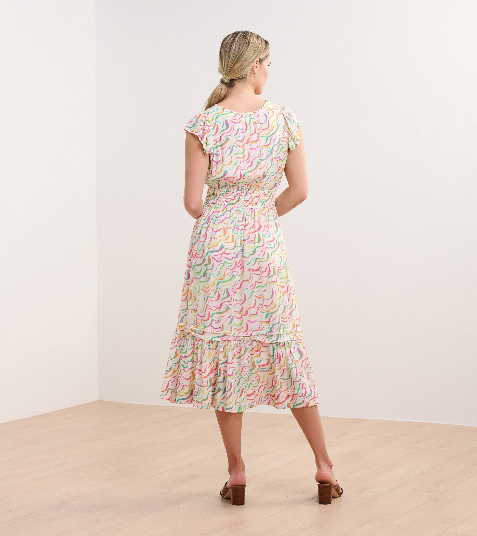 Back view of a midi dress featuring wavy stripes in pastel colors, with a ruffled hem and short sleeves.