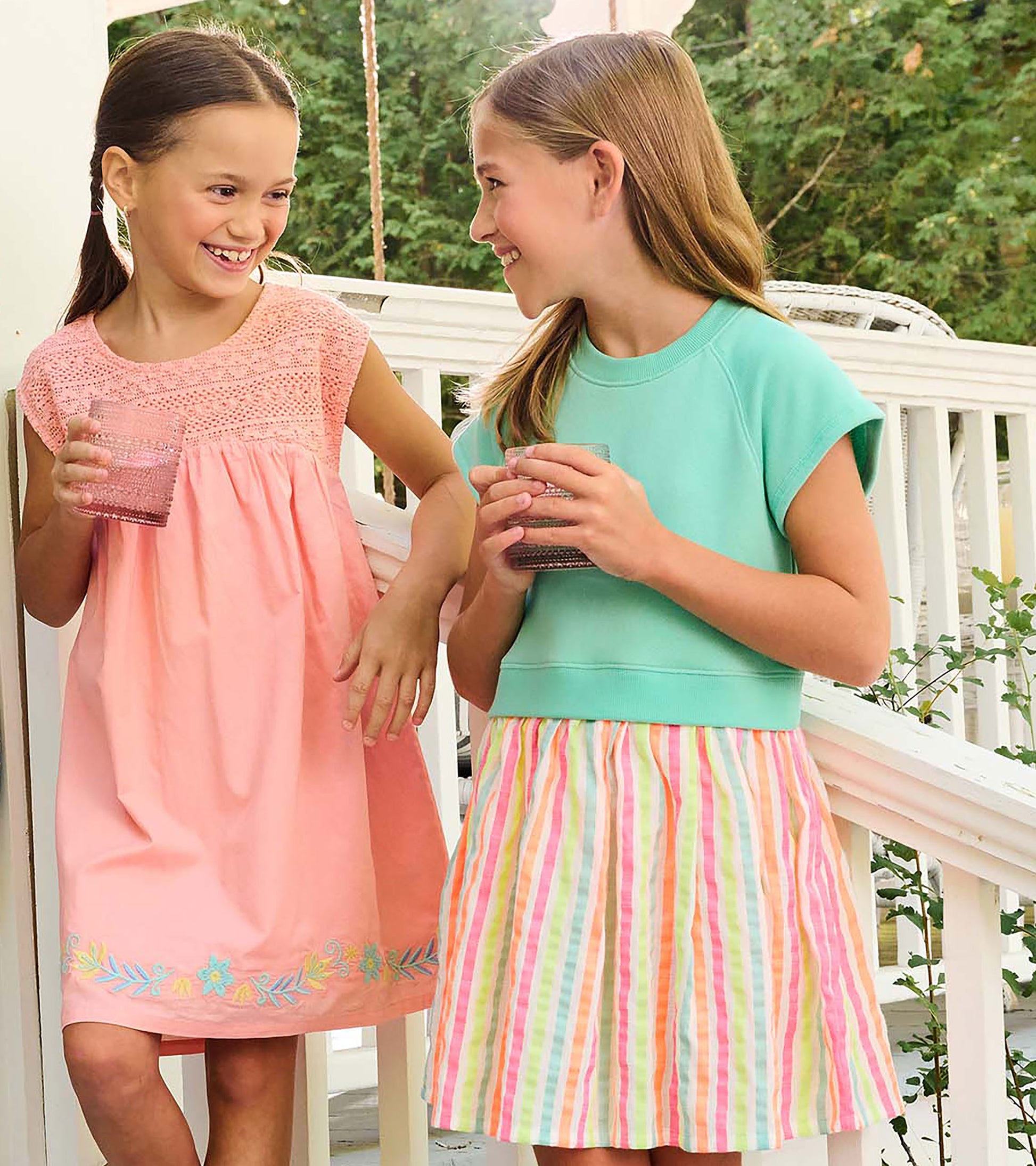 Girl wearing an apricot blush dress with crochet bodice and floral embroidery at the hem, shown on a porch
