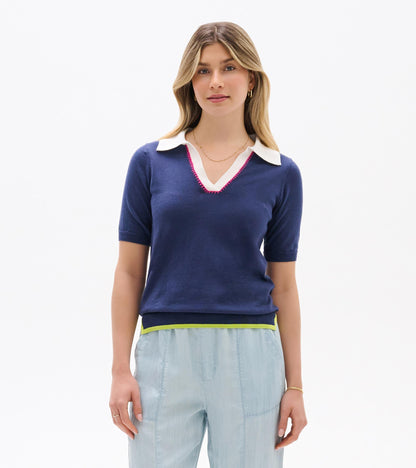 Woman wearing a navy short-sleeve knit top with white Johnny collar and pink trim, front view.