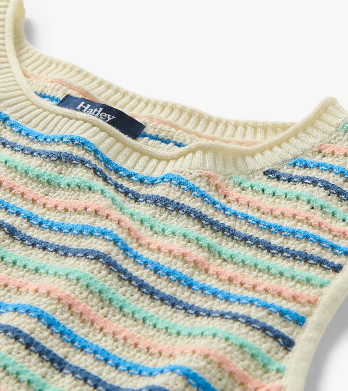 Close-up of ribbed crew neck and textured knit with blush, aqua, and blue stripes on a cream base