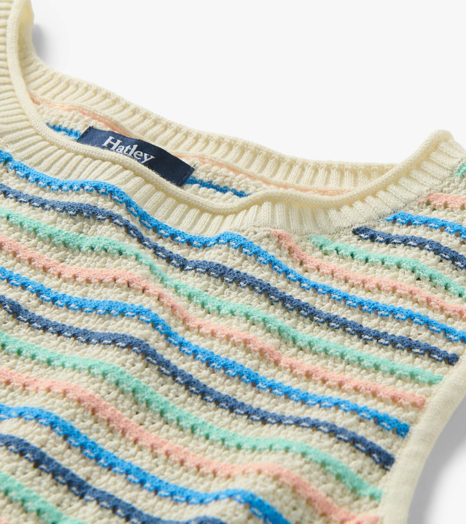 Close-up of ribbed crew neck and textured knit with blush, aqua, and blue stripes on a cream base