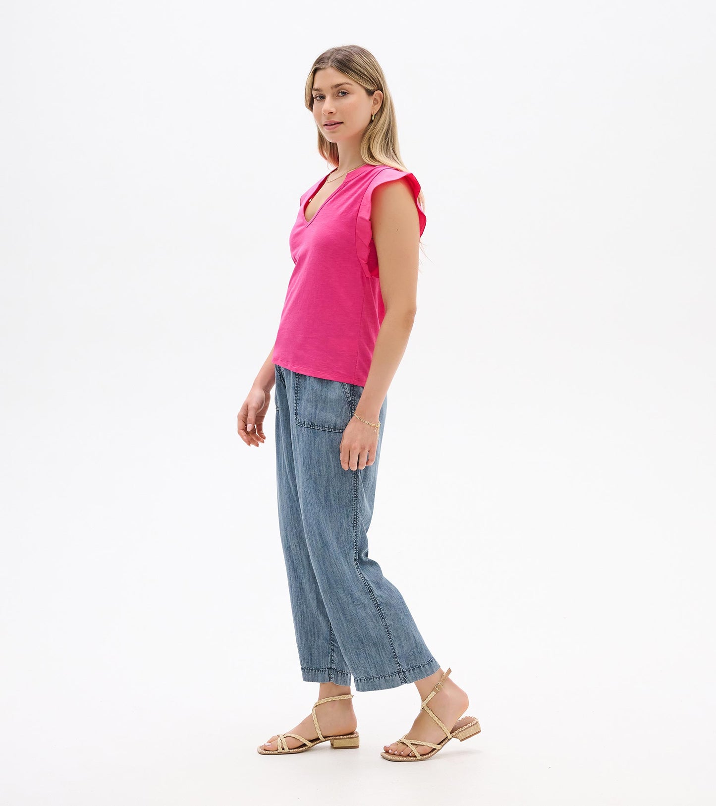 Bright pink sleeveless V-neck tank top with flutter sleeves, shown on a model in side view.