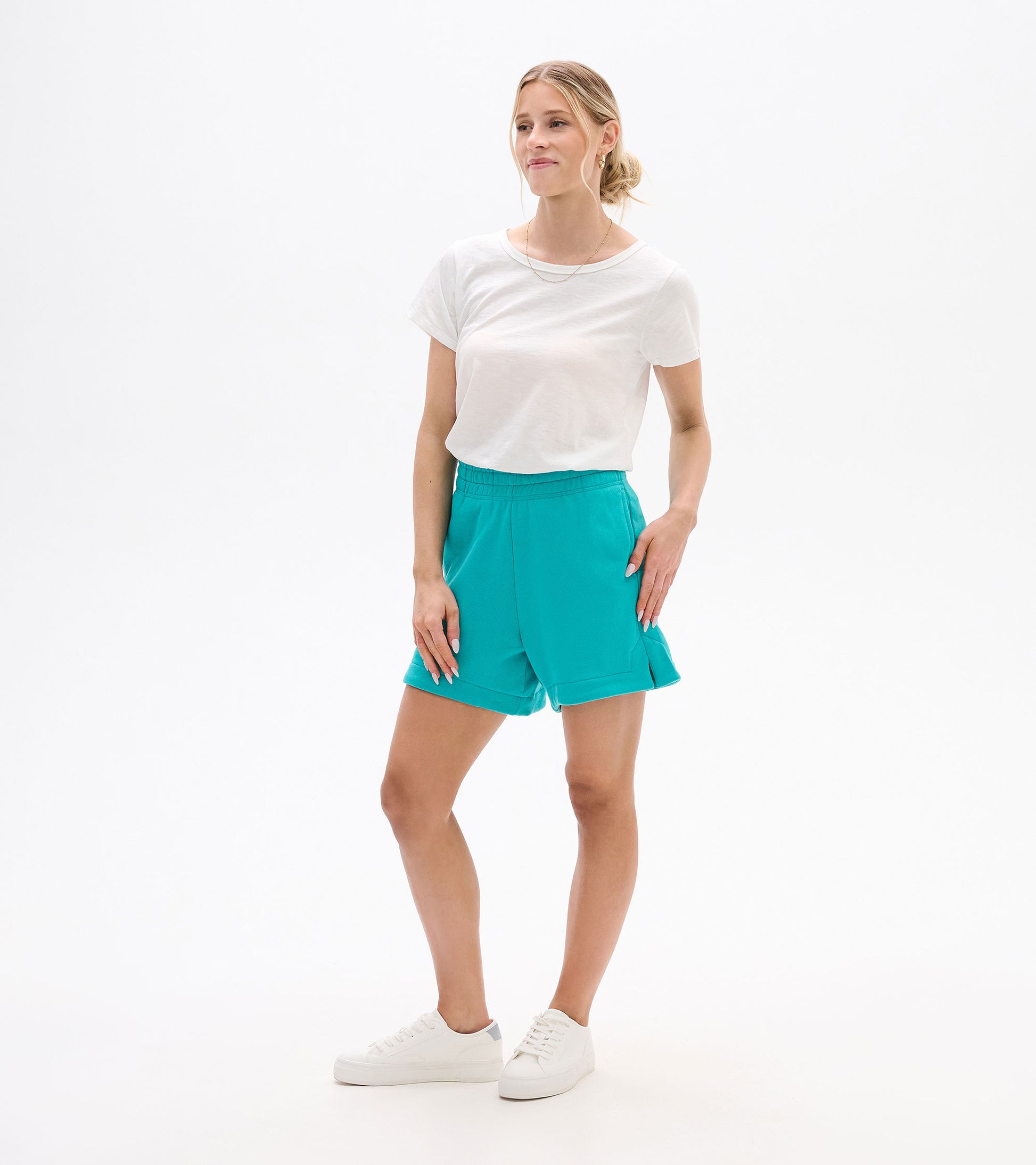 Woman wearing bright turquoise pull-on shorts with elastic waistband and side slits, front view