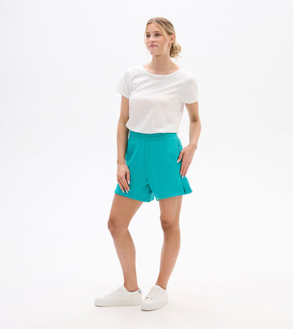 Woman wearing bright turquoise pull-on shorts with elastic waistband and side slits, front view