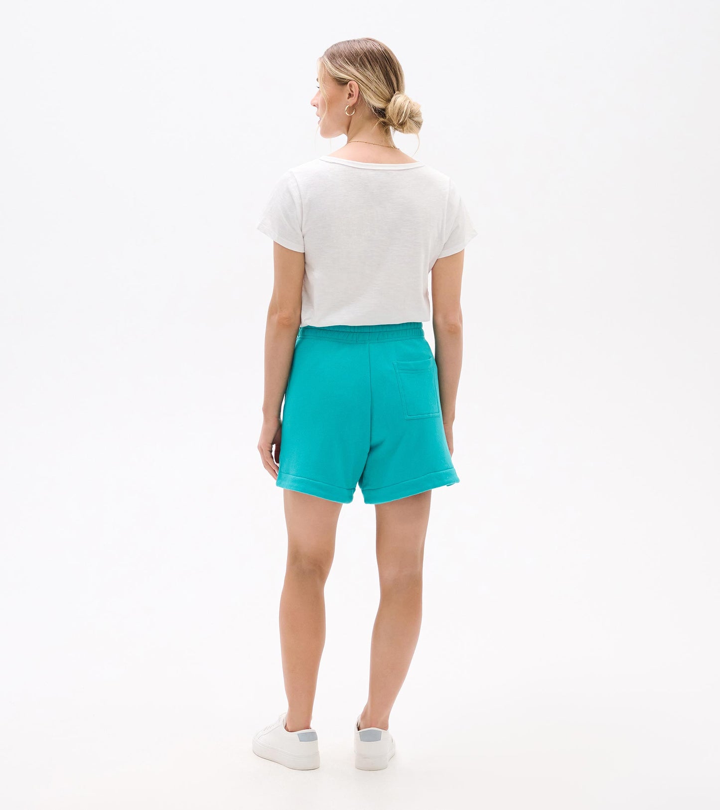 Turquoise high-waisted shorts with rolled hems and back patch pocket, shown from the back on a model