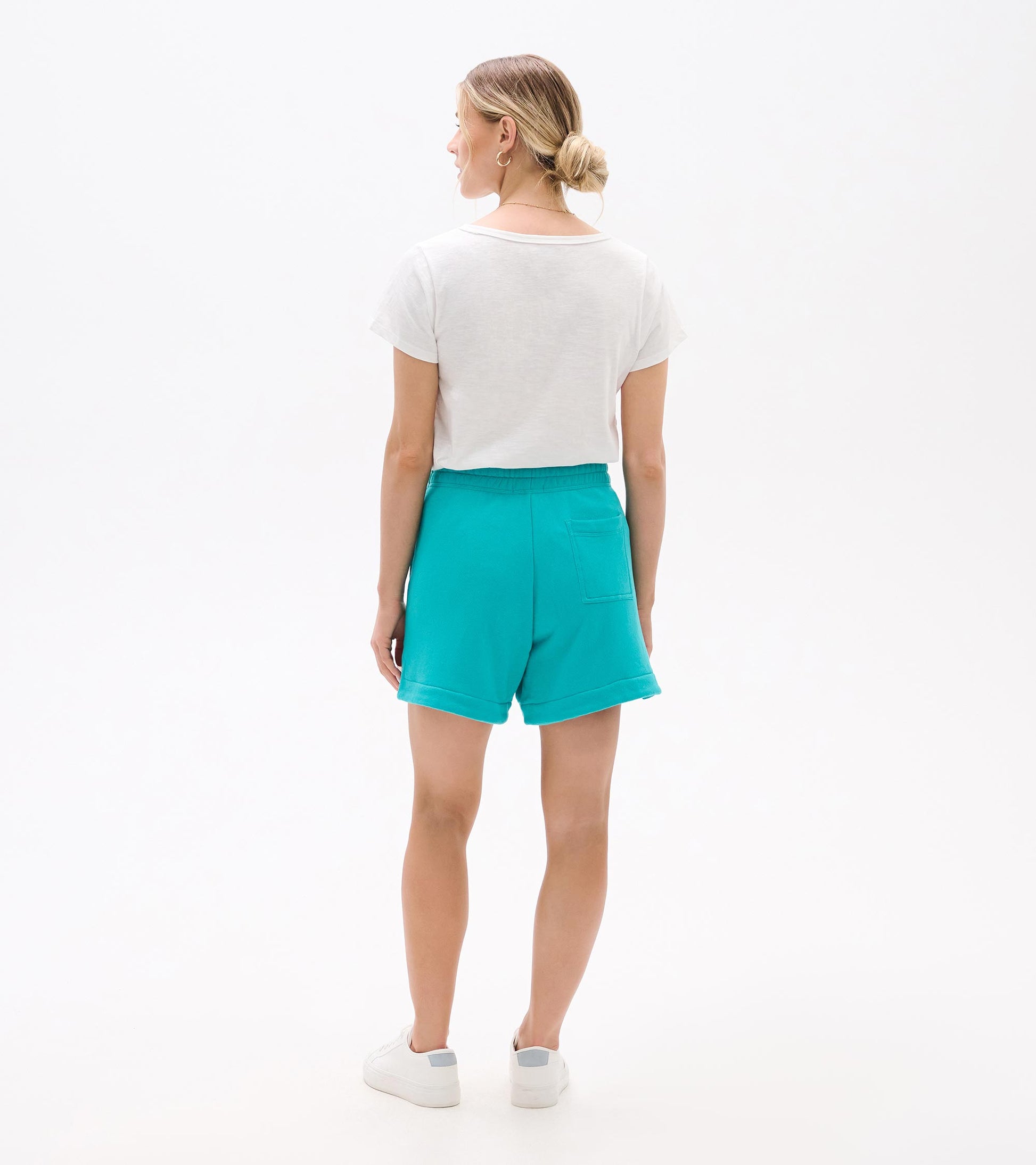 Turquoise high-waisted shorts with rolled hems and back patch pocket, shown from the back on a model