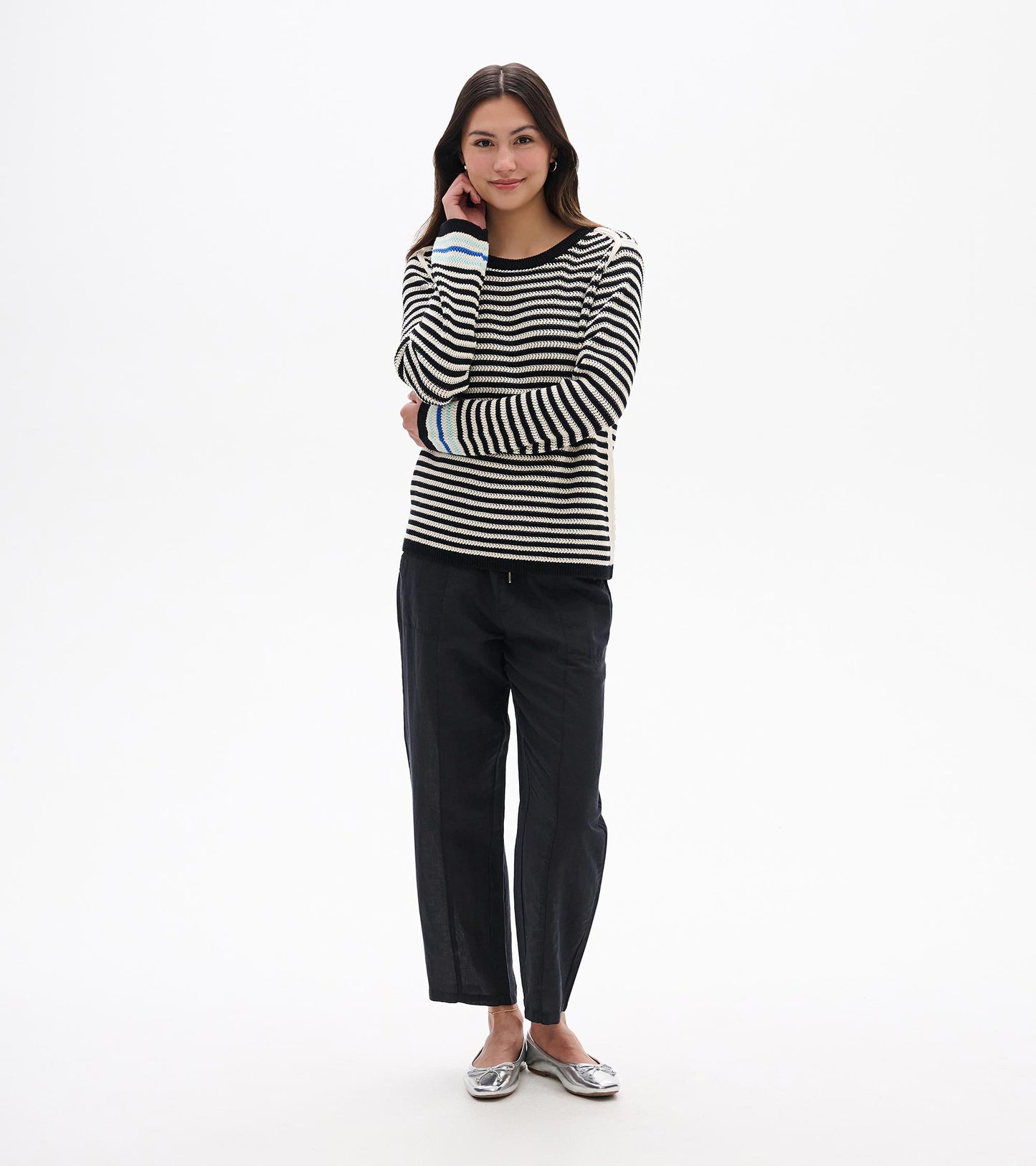 Front view of black and white striped pointelle sweater with black trim and blue cuff accents