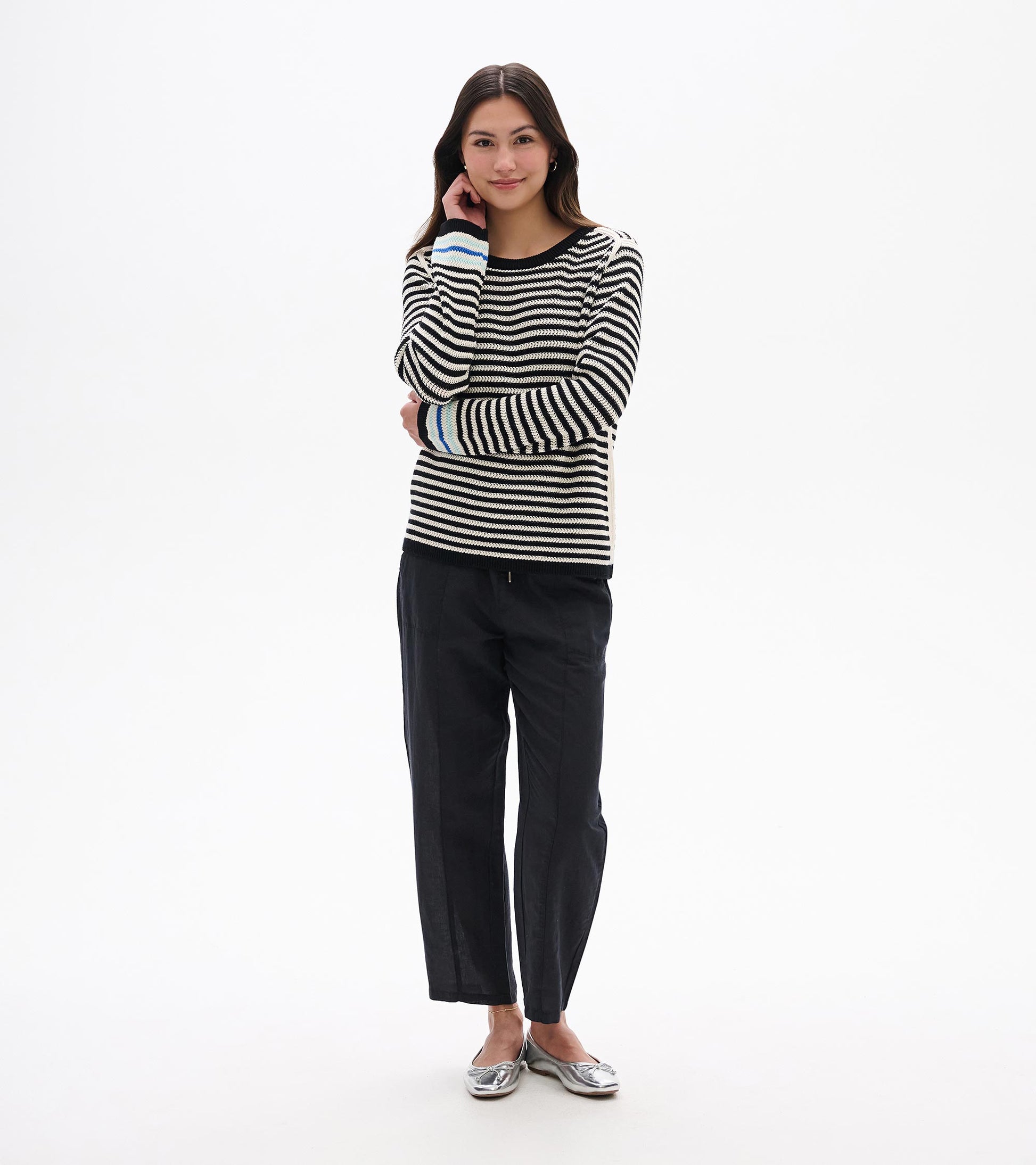 Front view of black and white striped pointelle sweater with black trim and blue cuff accents